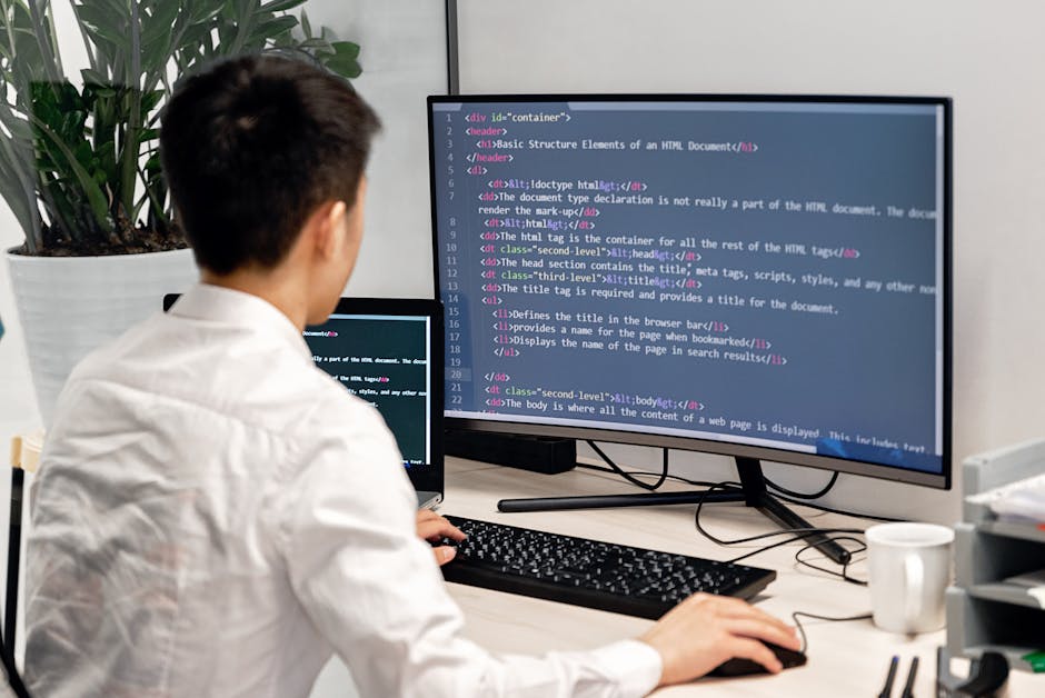 Adult male programmer coding on dual monitors in a modern indoor workspace